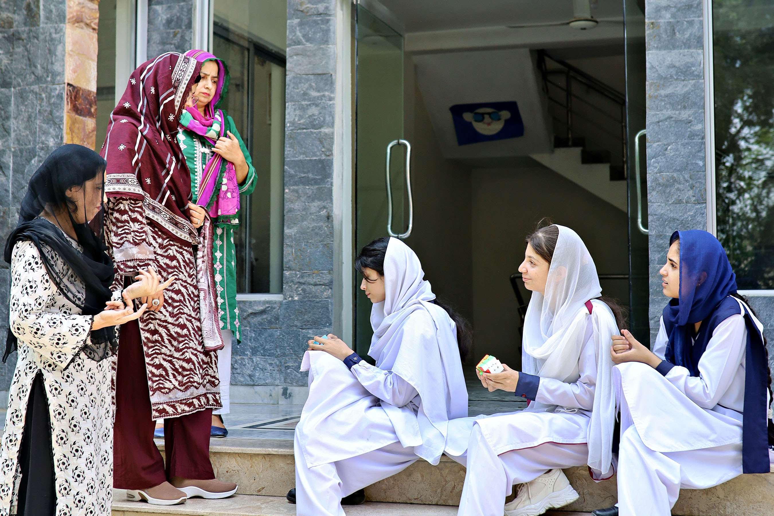 Teachers talking with senior students on the steps outside the school