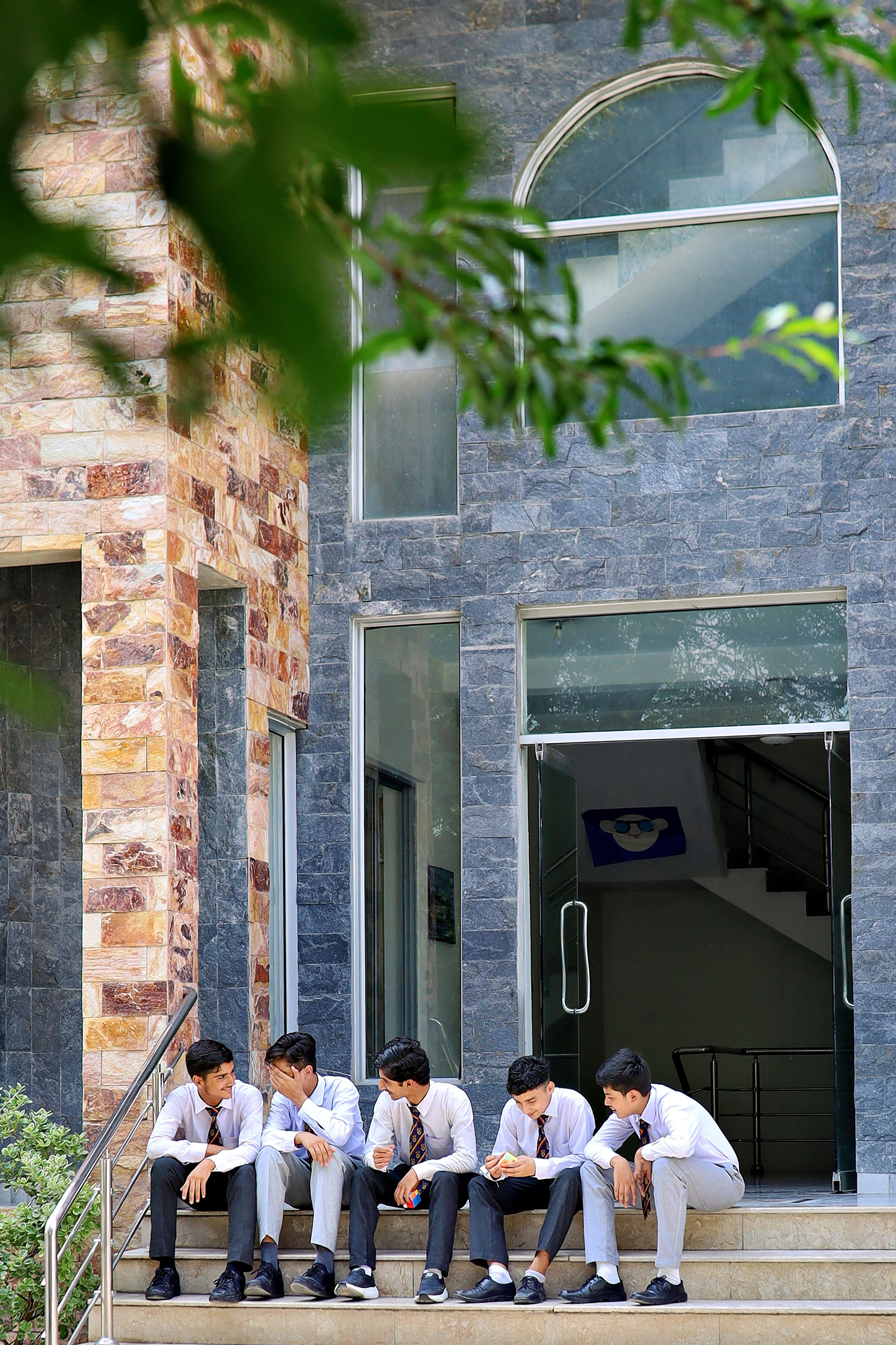 Students sitting together on the steps outside the school building